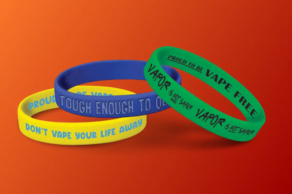 Colorful silicone wristbands with anti-vaping messages displayed against a red gradient background.