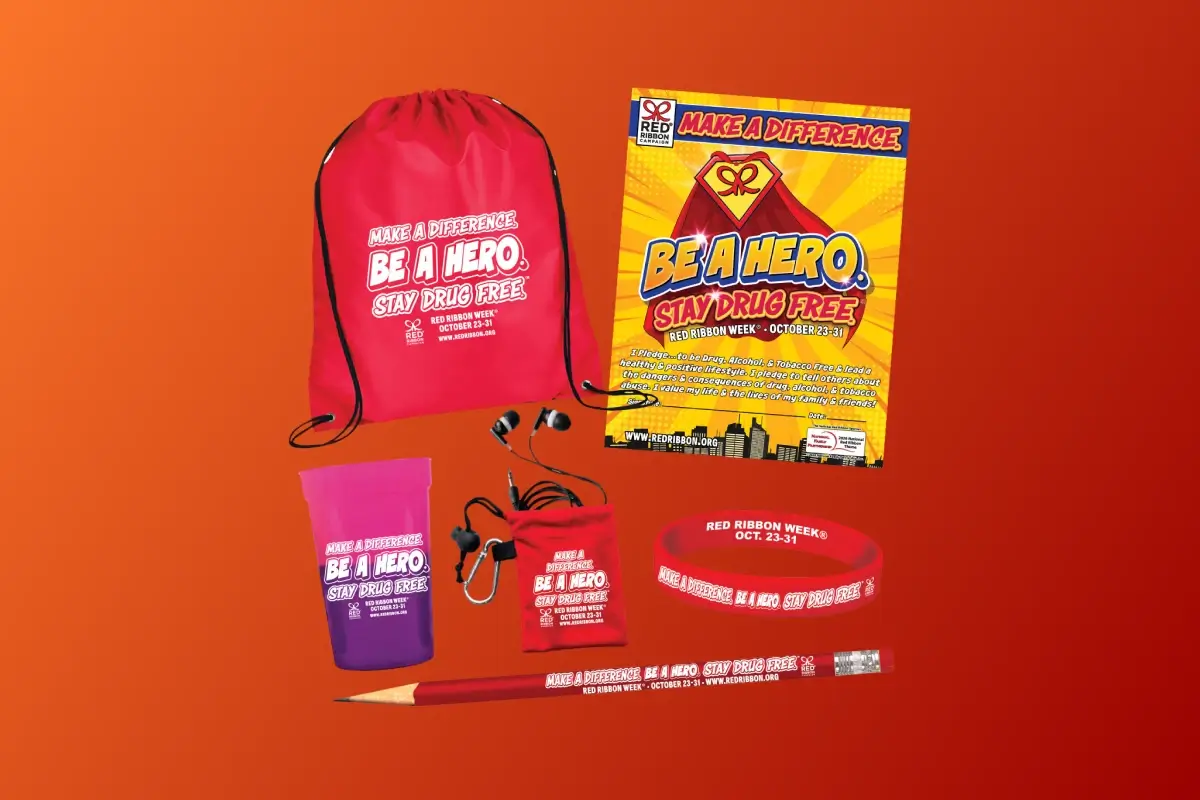 Red Ribbon Week 'Make a Difference. Be a Hero. Stay Drug Free.' promotional kit including a red drawstring bag, pledge poster, color-changing cup, earbud pouch with earbuds, silicone wristband, and pencil, all branded with the Red Ribbon Week October 23-31 theme.